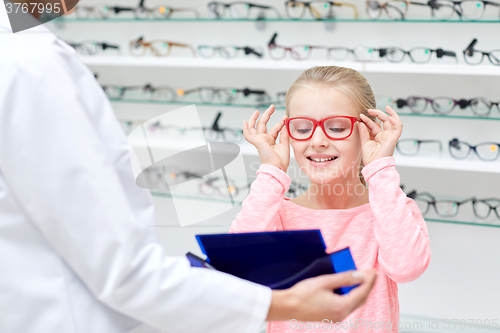 Image of optician and girl choosing glasses at optics store