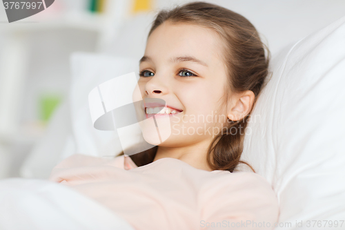 Image of happy smiling girl lying awake in bed at home