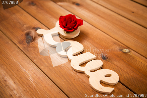 Image of close up of word love cutout with red rose on wood