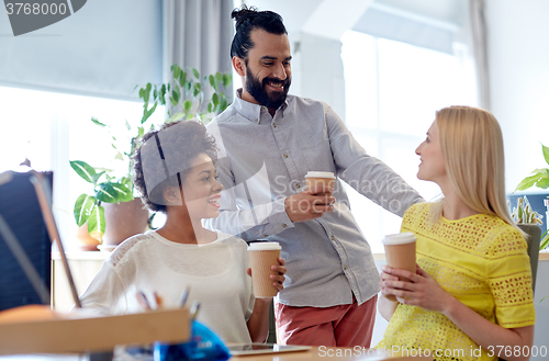 Image of happy creative team drinking coffee in office