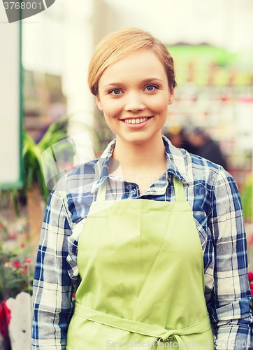 Image of happy woman with flowers in greenhouse