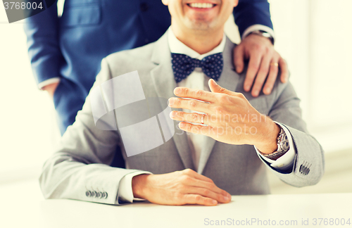 Image of close up of male gay couple with wedding rings on