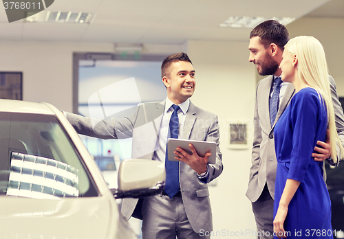 Image of happy couple with car dealer in auto show or salon