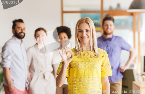 Image of happy woman showing ok over creative office team