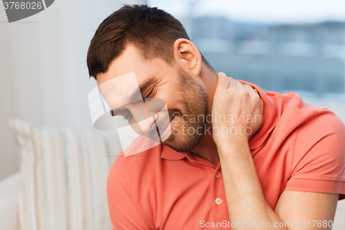 Image of unhappy man suffering from neck pain at home