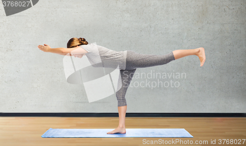 Image of woman making yoga warrior pose on mat