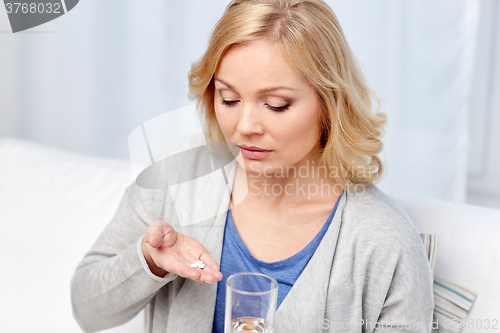 Image of woman with medicine and water glass at home