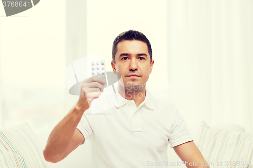 Image of man showing pack of pills at home