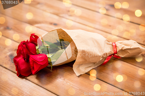 Image of close up of red roses bunch wrapped into paper