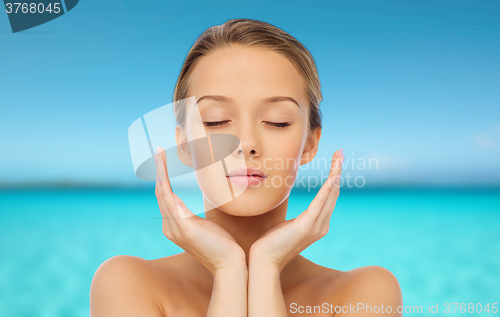 Image of young woman face with hands over sea and sky