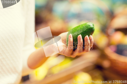 Image of close up of woman hand holding avocado in market