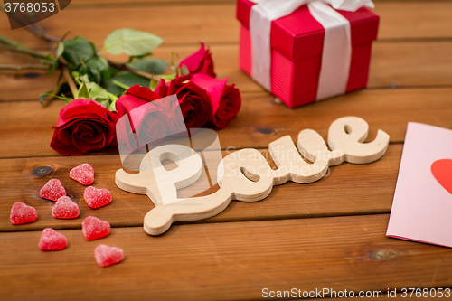 Image of close up of gift box, red roses and greeting card