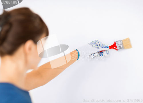 Image of woman with paintbrush colouring the wall