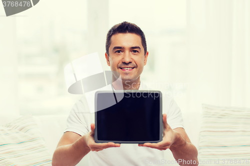 Image of smiling man showing tablet pc blank screen at home