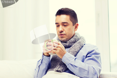 Image of ill man with flu drinking hot tea from cup at home