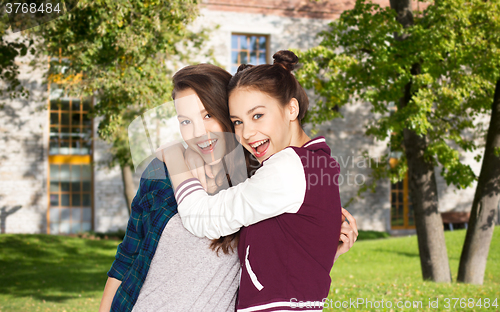 Image of happy teenage student girls hugging over campus 