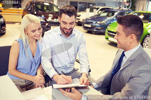 Image of happy couple with car dealer in auto show or salon