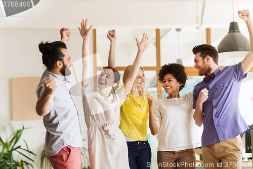 Image of happy creative team celebrating victory in office