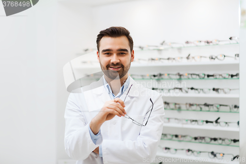 Image of man optician with glasses in coat at optics store