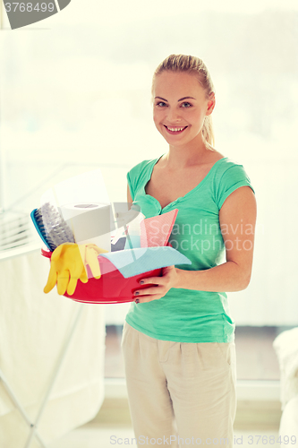 Image of happy woman holding cleaning stuff at home