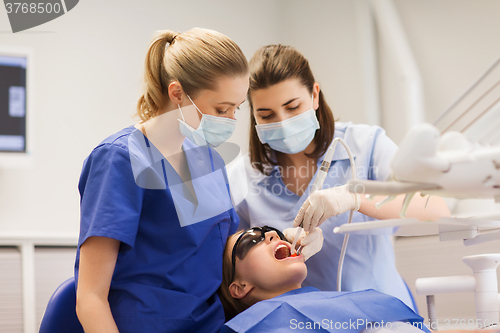 Image of female dentists treating patient girl teeth