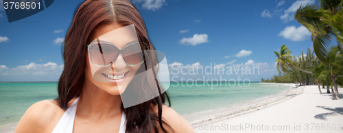 Image of smiling young woman with sunglasses on beach