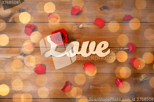 Image of close up of word love cutout with red rose on wood