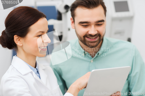 Image of optician with tablet pc and patient at eye clinic