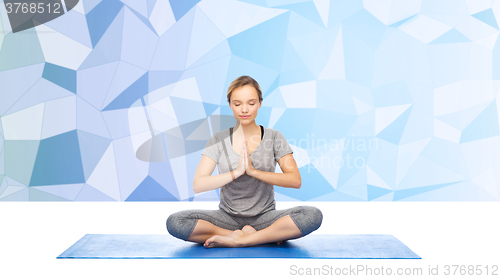 Image of woman making yoga meditation in lotus pose on mat