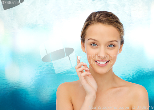 Image of happy young woman applying cream to her face