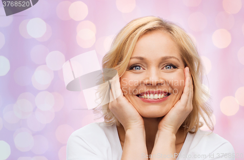 Image of smiling woman in white t-shirt touching her face