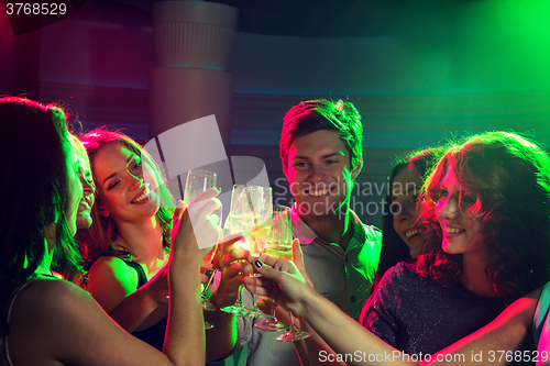 Image of smiling friends with glasses of champagne in club