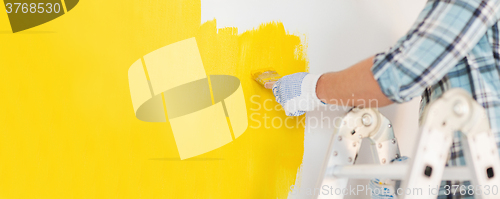 Image of close up of male in gloves painting a wall