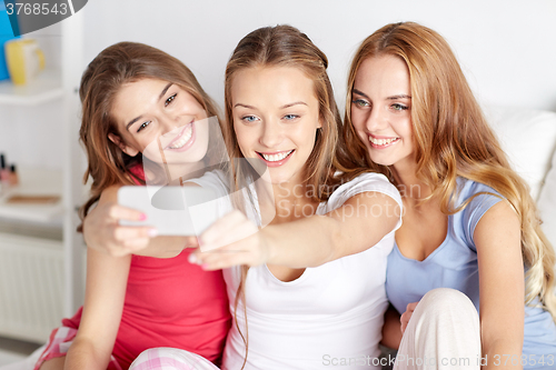 Image of teen girls with smartphone taking selfie at home