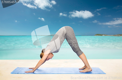 Image of woman making yoga dog pose on mat