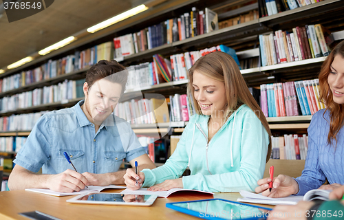 Image of happy students with tablet pc in library