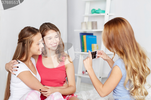 Image of teen girls with smartphone taking picture at home