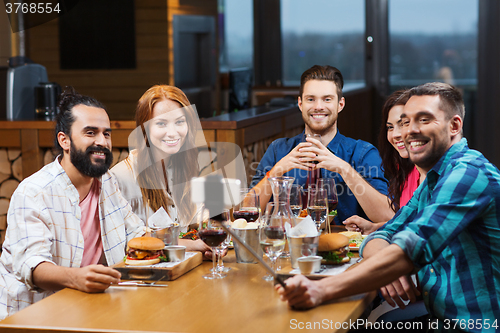 Image of friends taking selfie by smartphone at restaurant