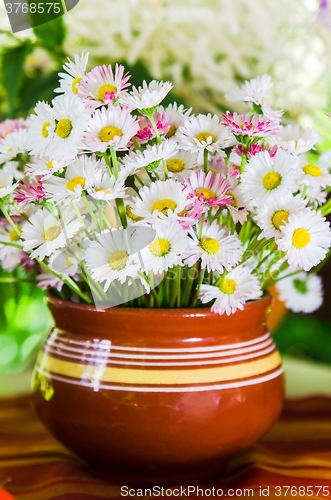 Image of A bouquet of daisies in a pot at the table