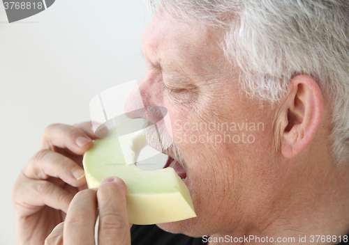 Image of Older man eating melon slice  