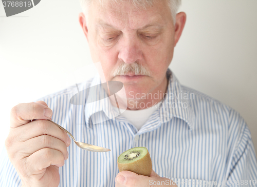 Image of Senior prepares to eat kiwifruit.  