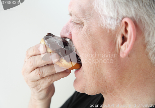 Image of Man takes bite of doughnut.  