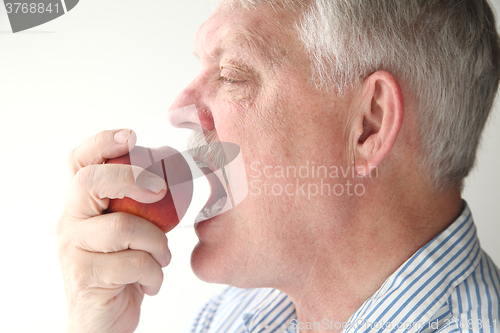 Image of Older man eating fresh peach	