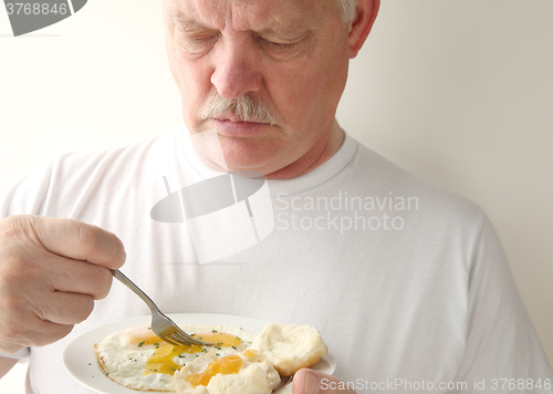 Image of Man having fried eggs and biscuits