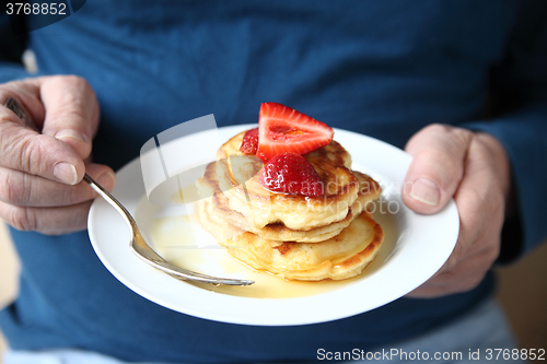 Image of Man with plate of strawberry-topped pancakes  