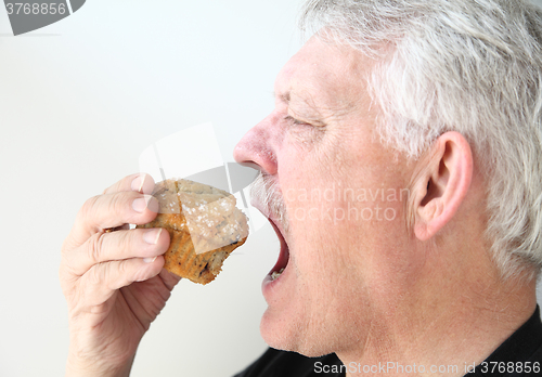 Image of Man eats blueberry muffin 