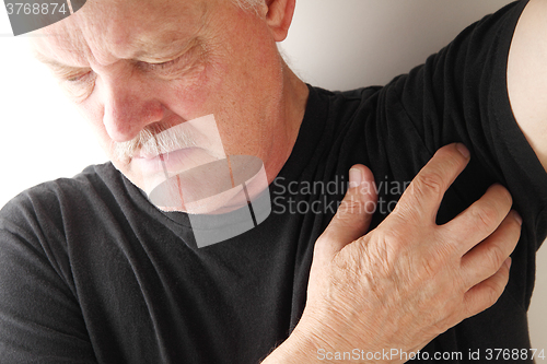 Image of Senior man scratches under his arm.