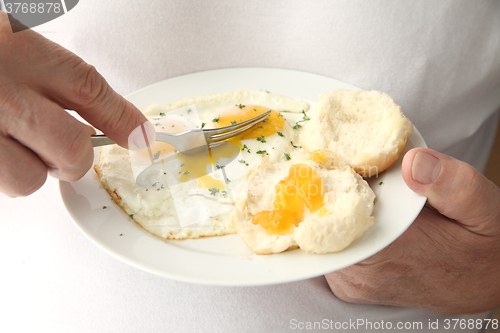 Image of Man cutting into fried eggs 