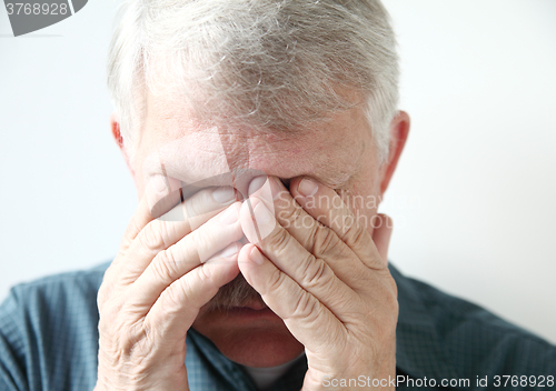 Image of Older man covers eyes with hands