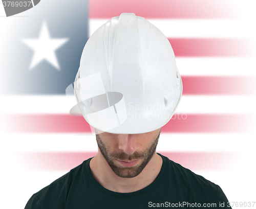 Image of Engineer with flag on background - Liberia